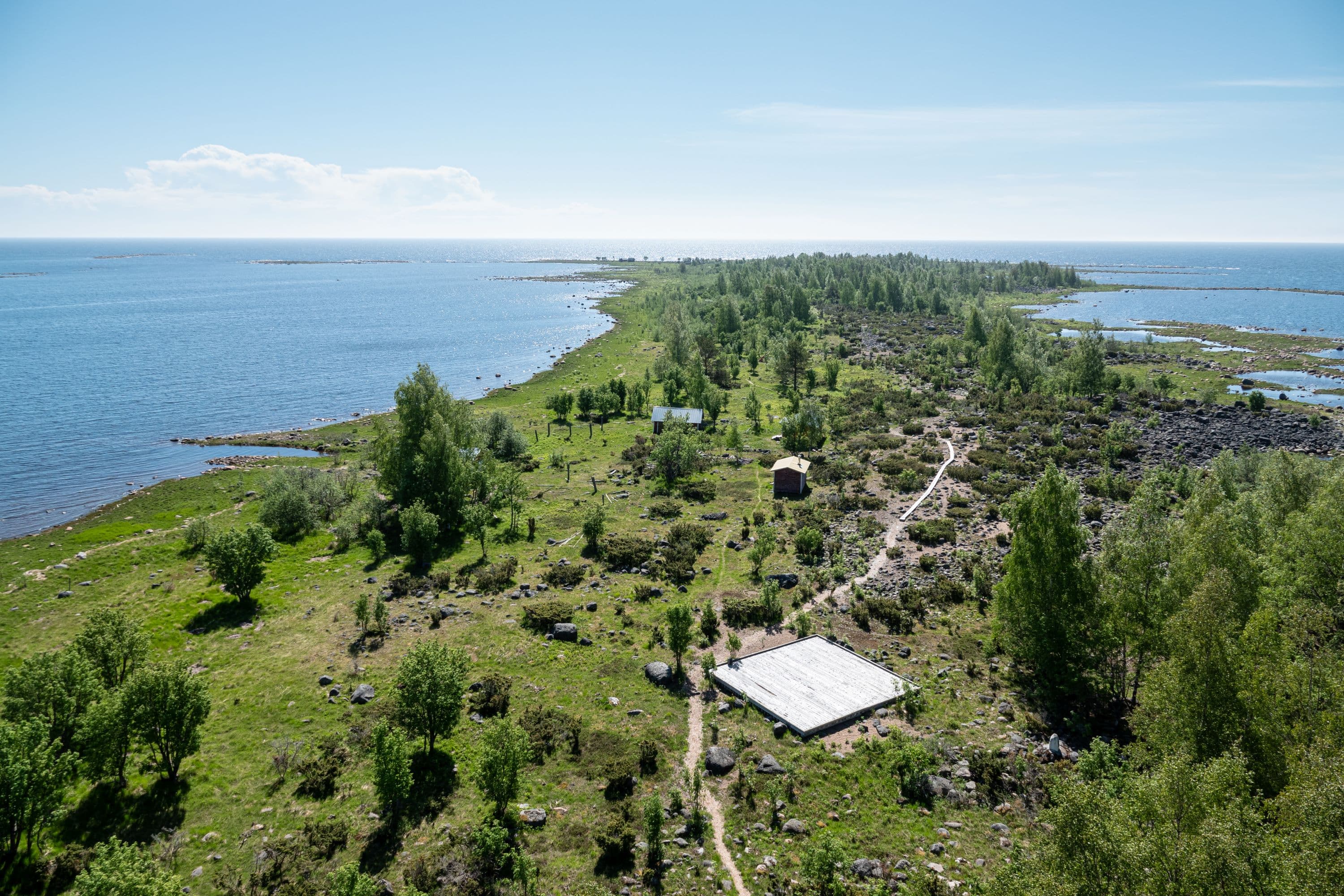 Kuva: Ismo Lampi Kapea saari hehkuu vihreänä yläviistosta otetussa kuvassa. Saaren molemmin puolin on sinistä merta.