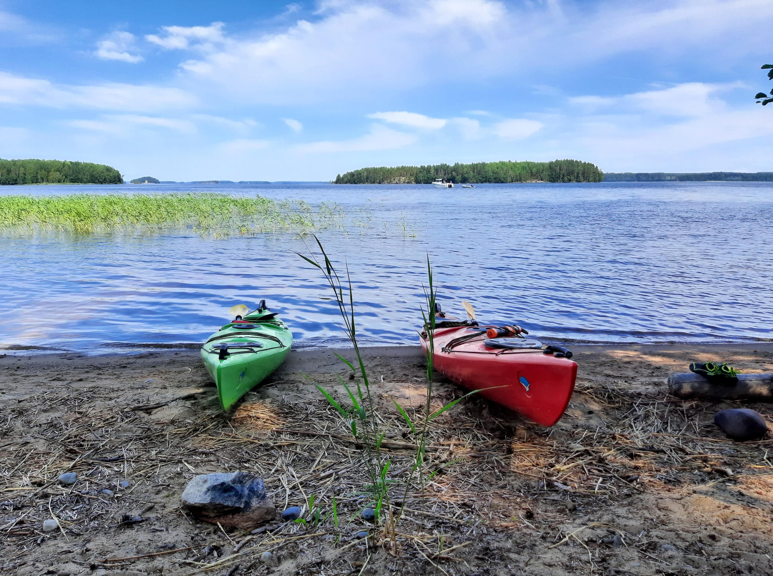 Kuva: Etti Kantola Kaksi kajakkia vedettynä rannalle. Järvellä näkyy kaislikkoa ja kauempana saaria.