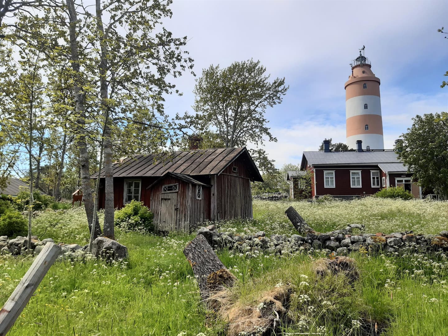 Kuva: Kirsi Nikkola Punaiseksi maalattuja puisia rakennuksia, taustalla näkyy punavalkoraidallinen majakka.