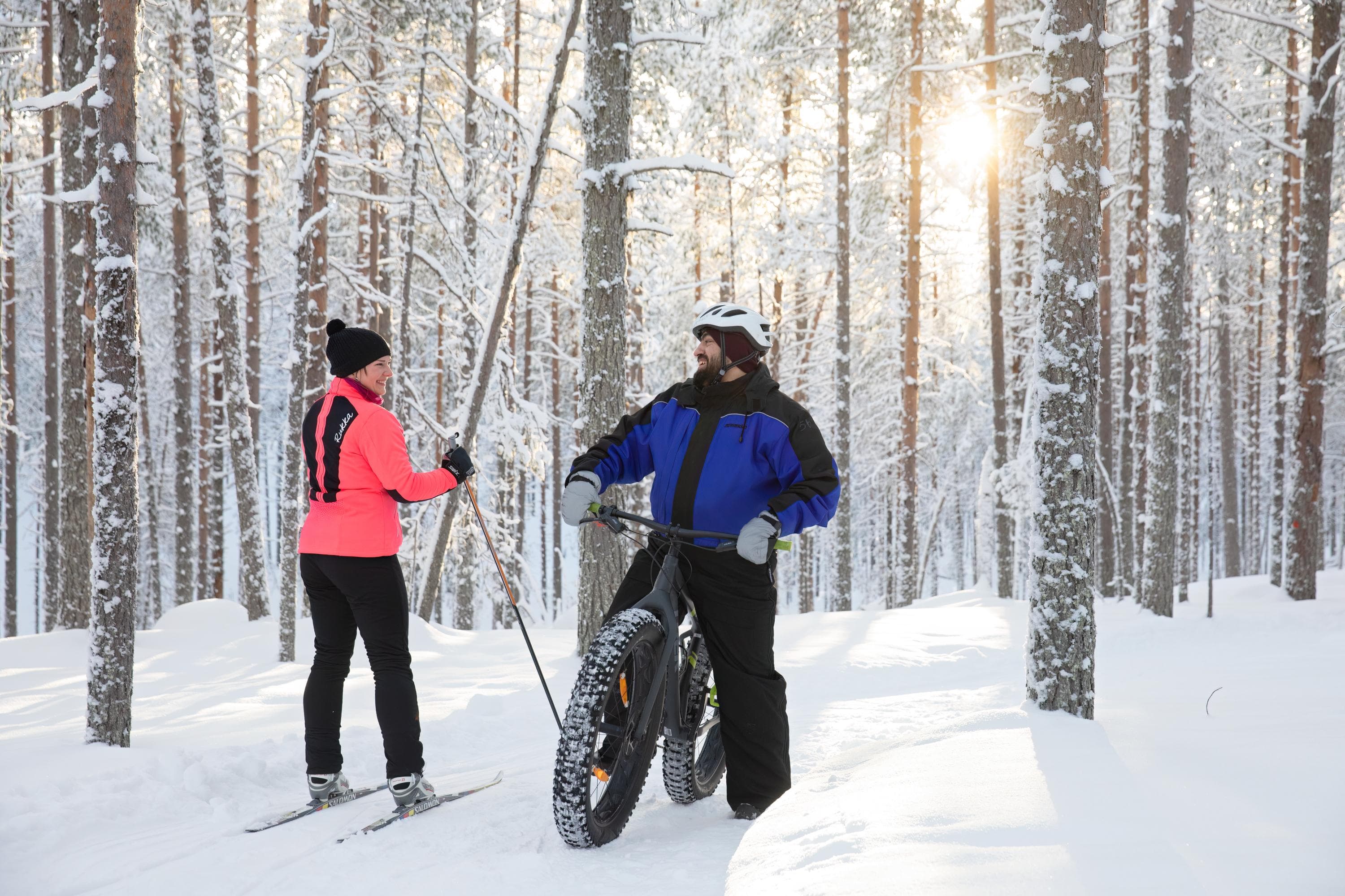 Kuva: Katri Lehtola / Keksi Maastohiihtäjä ja fatbike-pyöräilijä ovat pysähtyneet juttelemaan reitillä talvisessa metsässä.