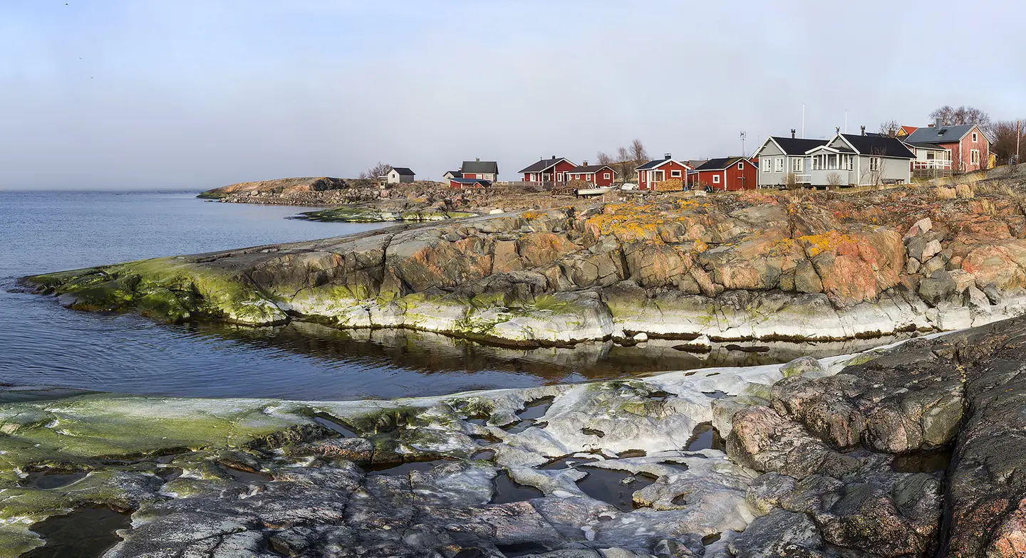 Kuva: Jari Kostet Kallioita meren rannalla, taaempana punaisia rakennuksia