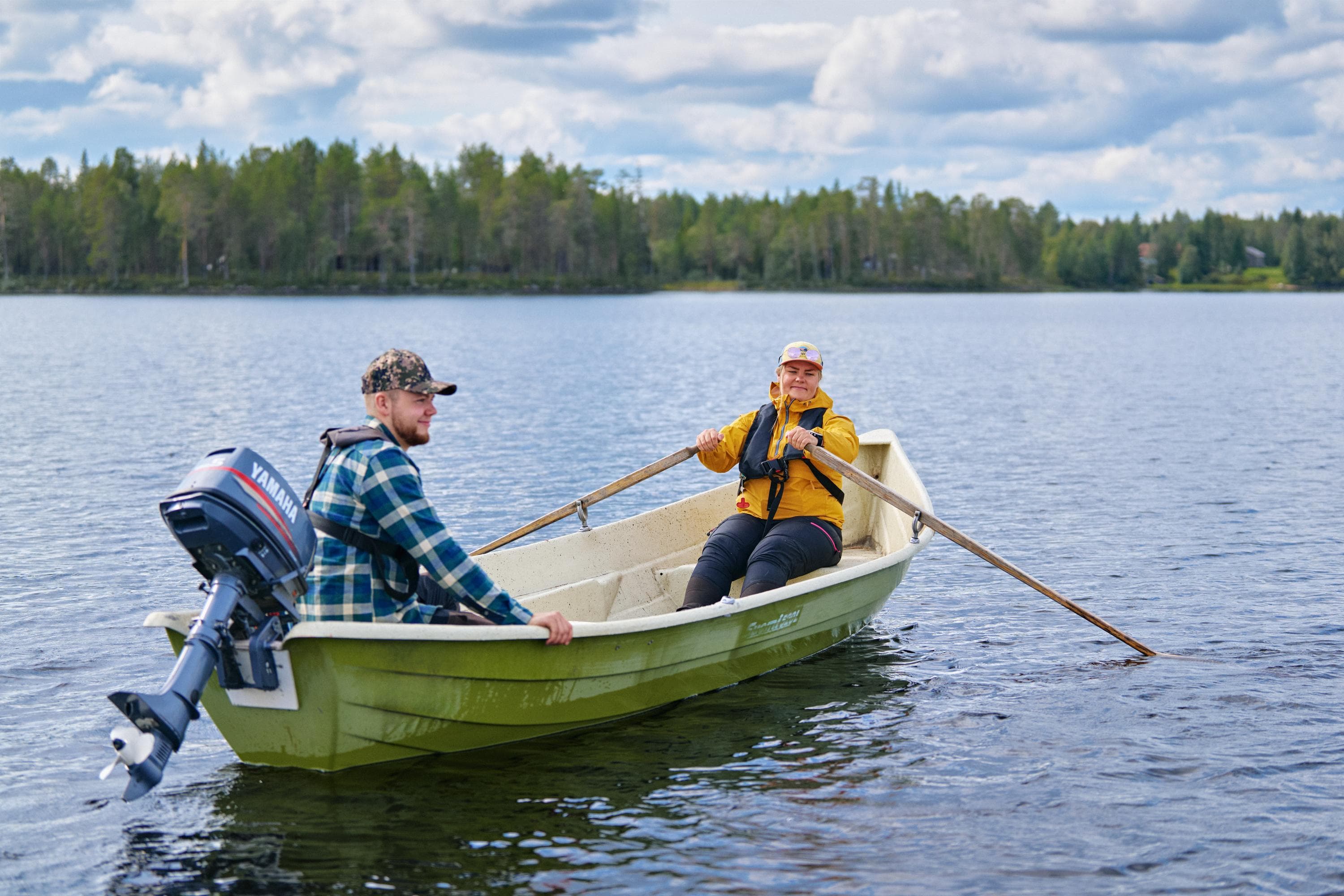 Perämoottorivene pohjoisella järvellä, moottori ilmassa. Kyydissä kaksi kalastajaa, joista toinen soutaa.