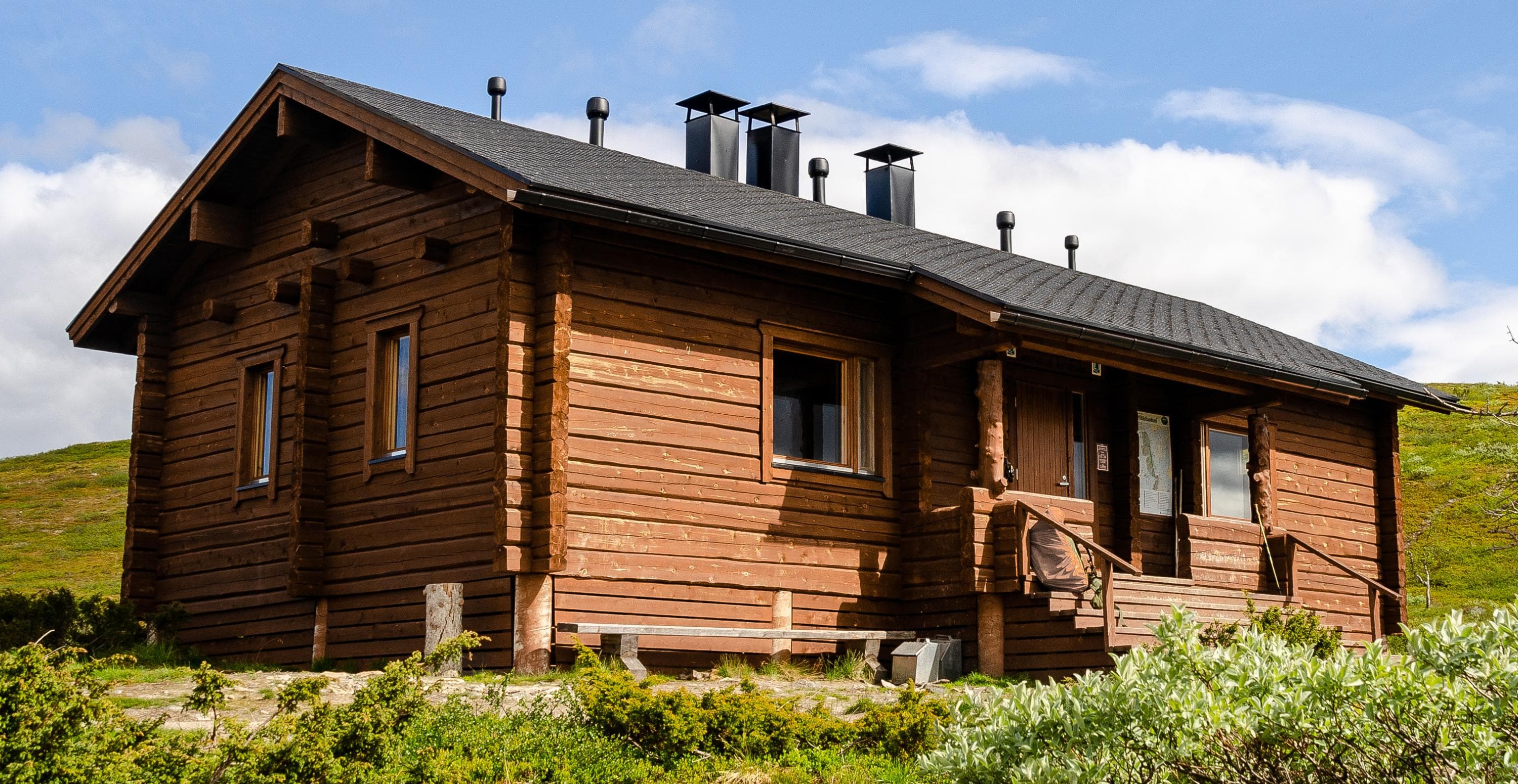 Kuva: Joonas Talka Puinen tupa, jonka ympärillä vihreää kasvillisuutta.