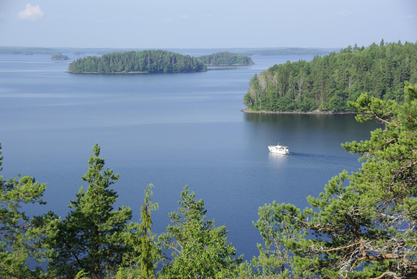 Image: Anne Pyykönen Summer Lake Scenery. A lake with a boat and forested islands.