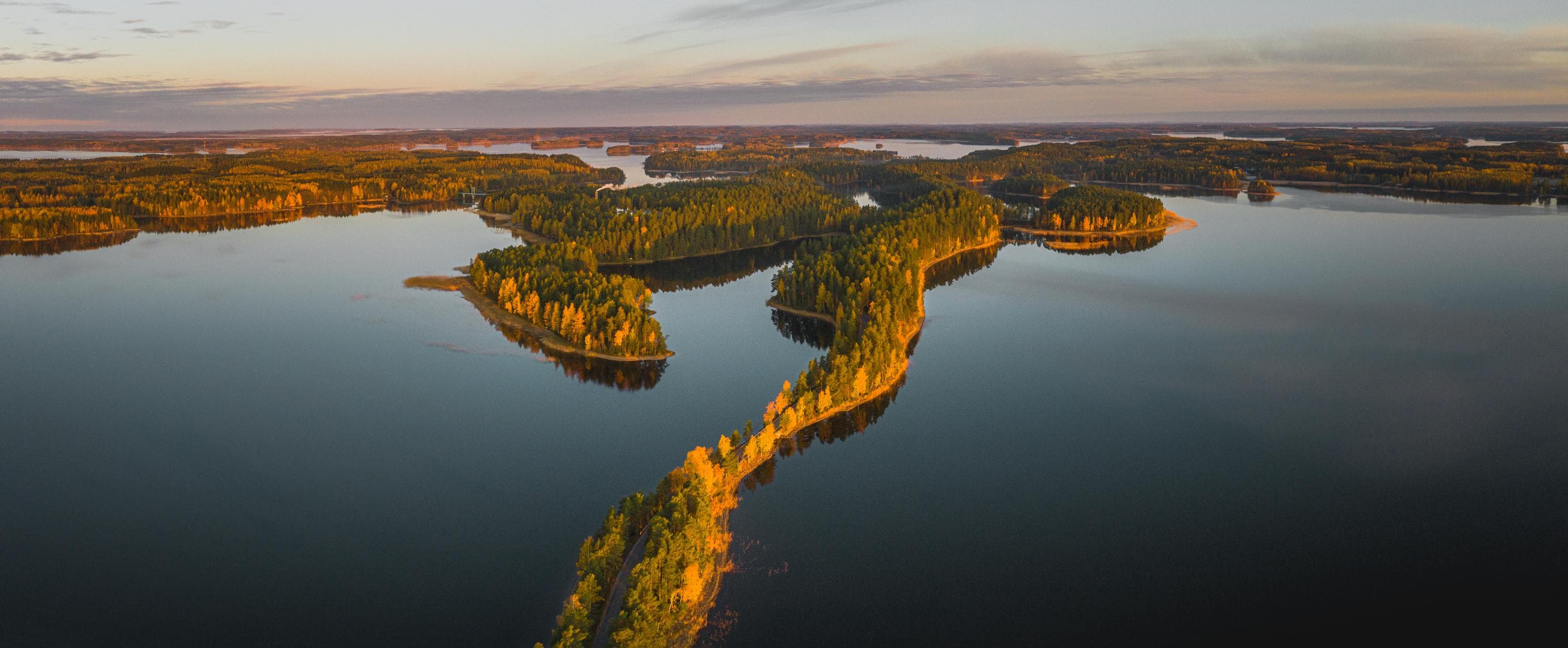 Bild: Jussi Silvennoinen En spegelblank sjö genombryts av en smal skogsklädd ås.