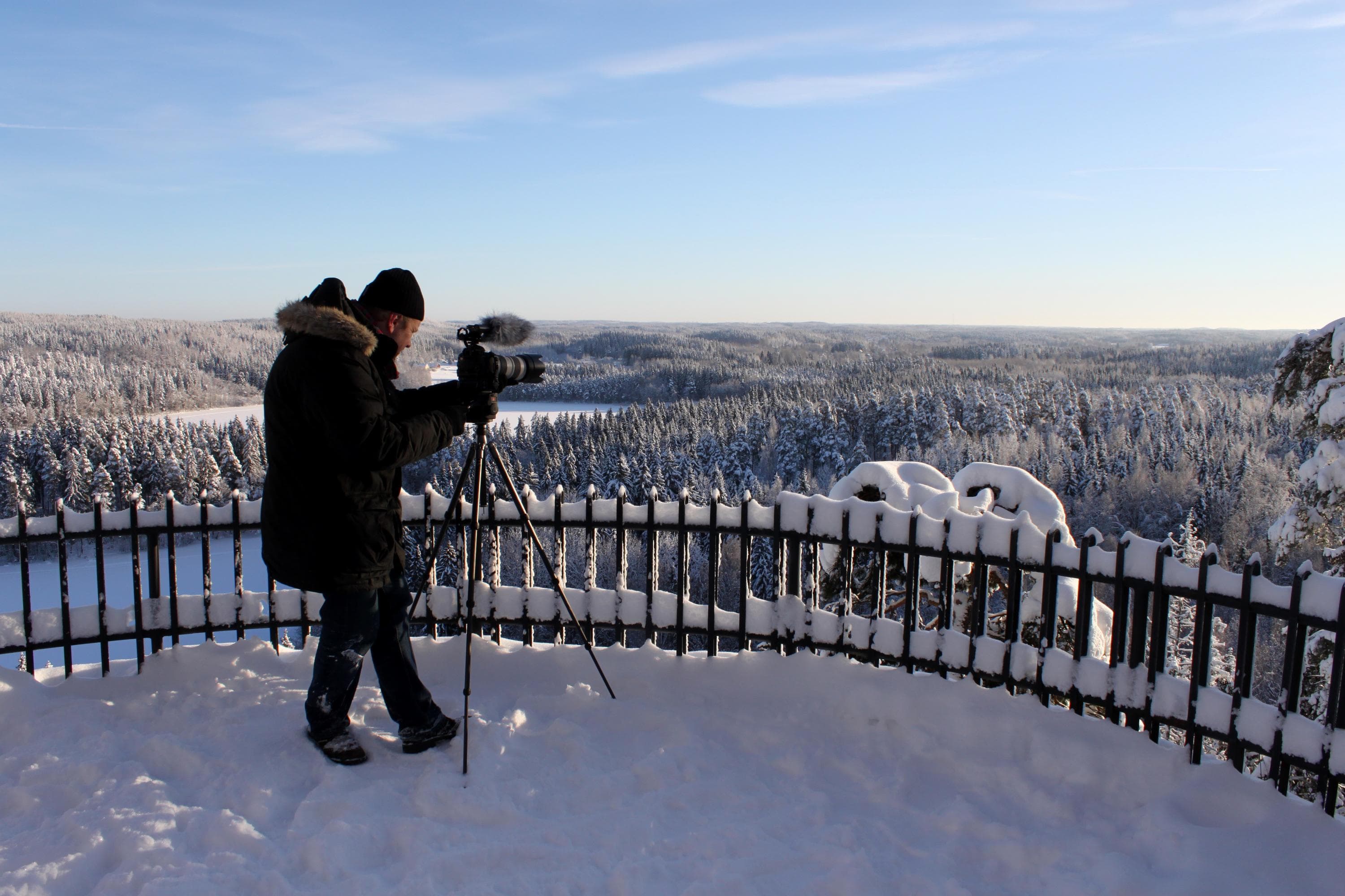 Bild: S-M Hiukkamäki En person i utsiktstornet med kameran på ett stativ. Kameran pekar mot den snöiga skogen.