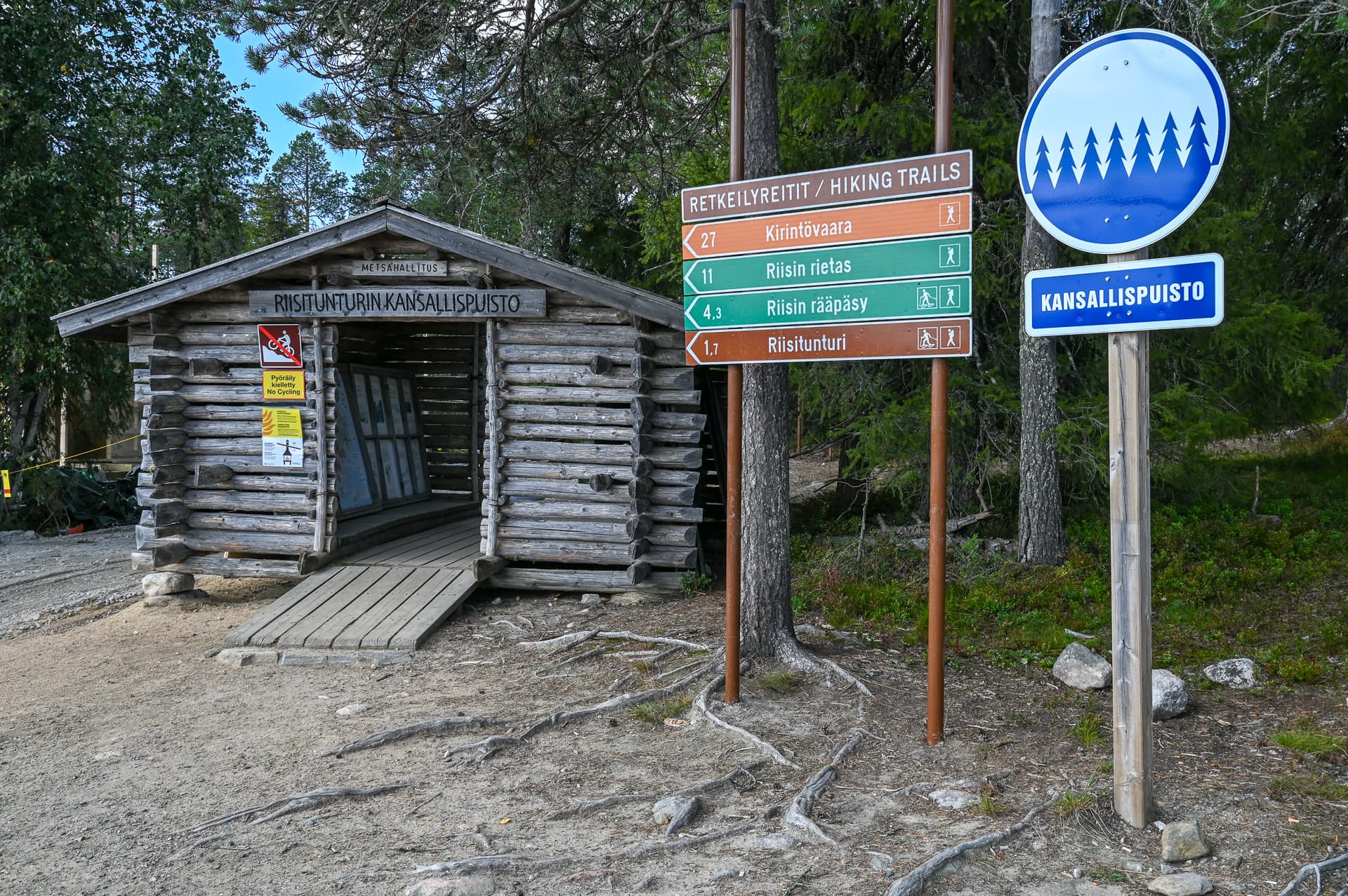 Bild: Riitta Tiermas Vid kanten av parkeringsplatsen finns ett informationstak, vägvisare och nationalparksmärke.