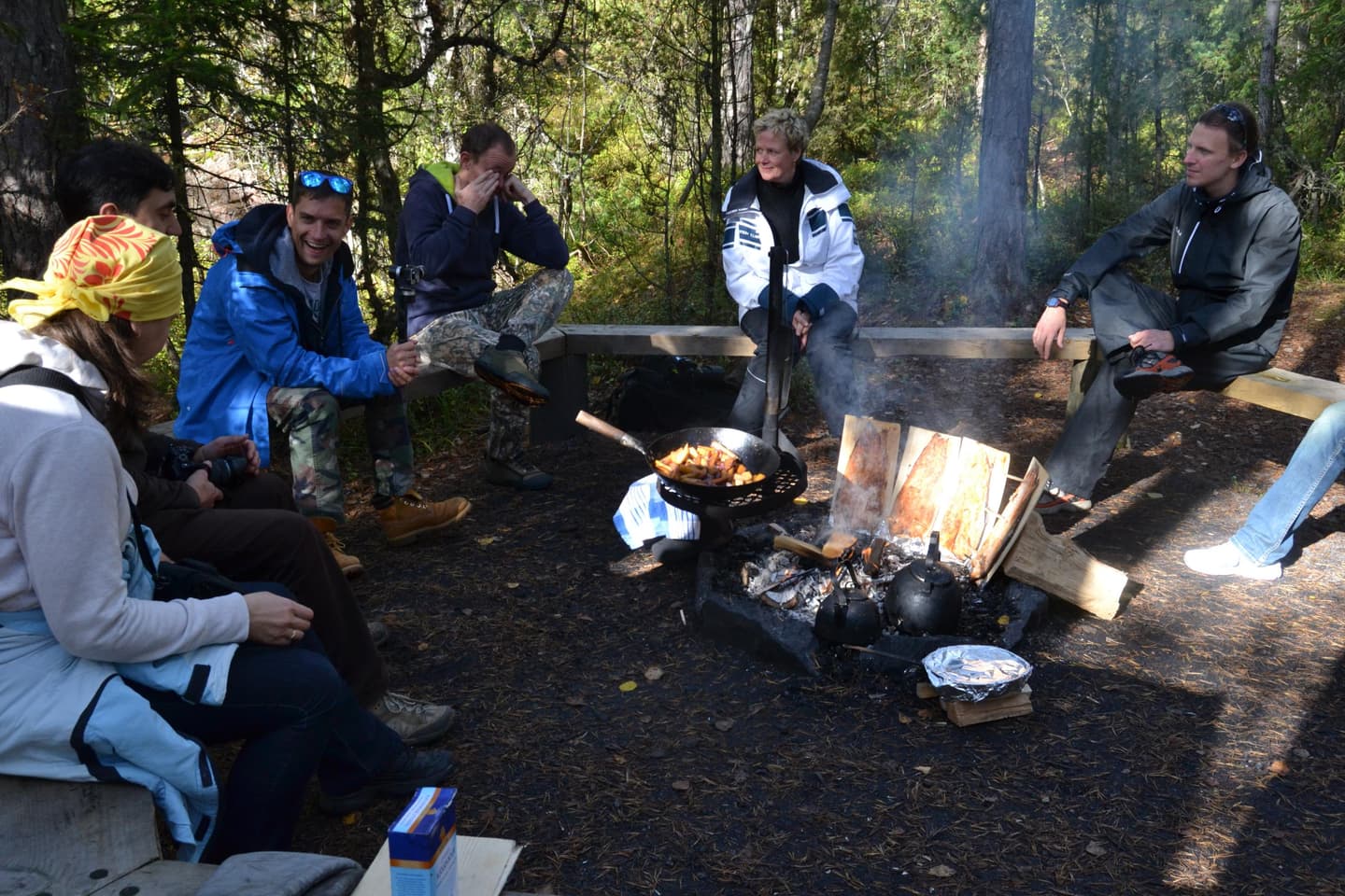 Image: Alina Tuomisto A group of people is sitting around the campfire and eating snacks.