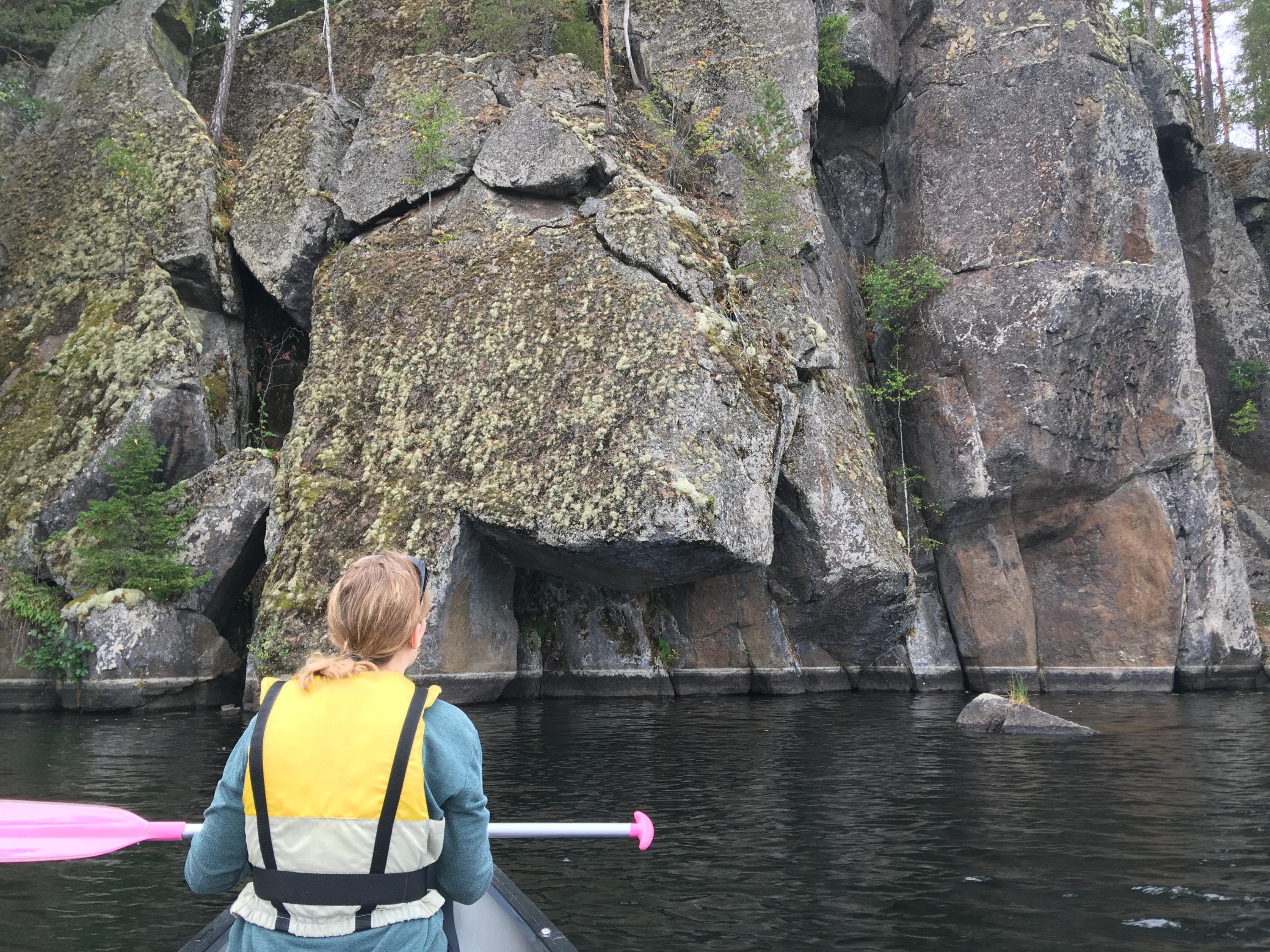Kuva: Maija Mikkola Retkeilijä melomassa ja katsomassa kallioseinämää.