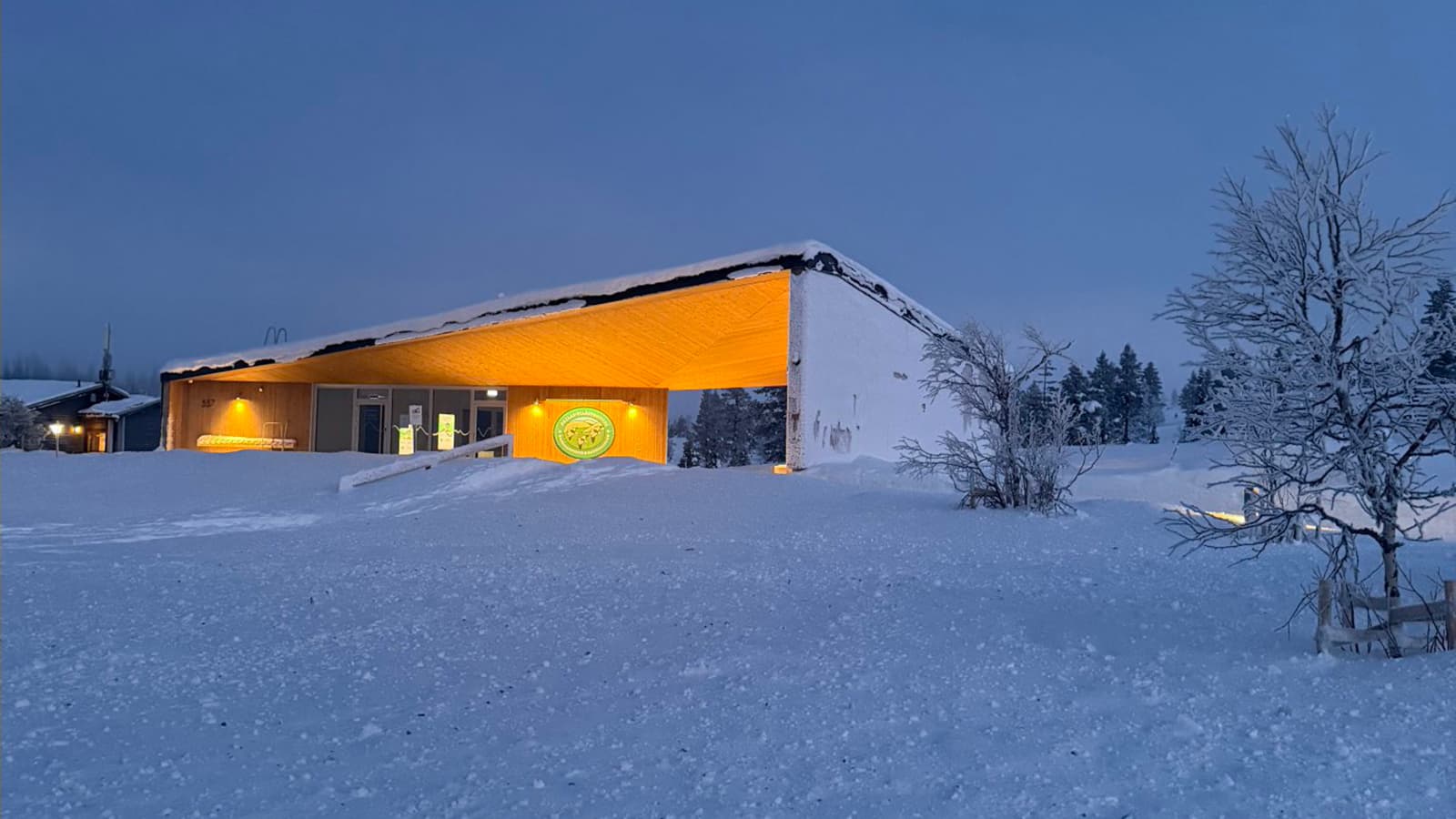 Kuva: Heta Kylmämaa Valaistu puinen rakennus, jonka seinässä on iso tunnus.